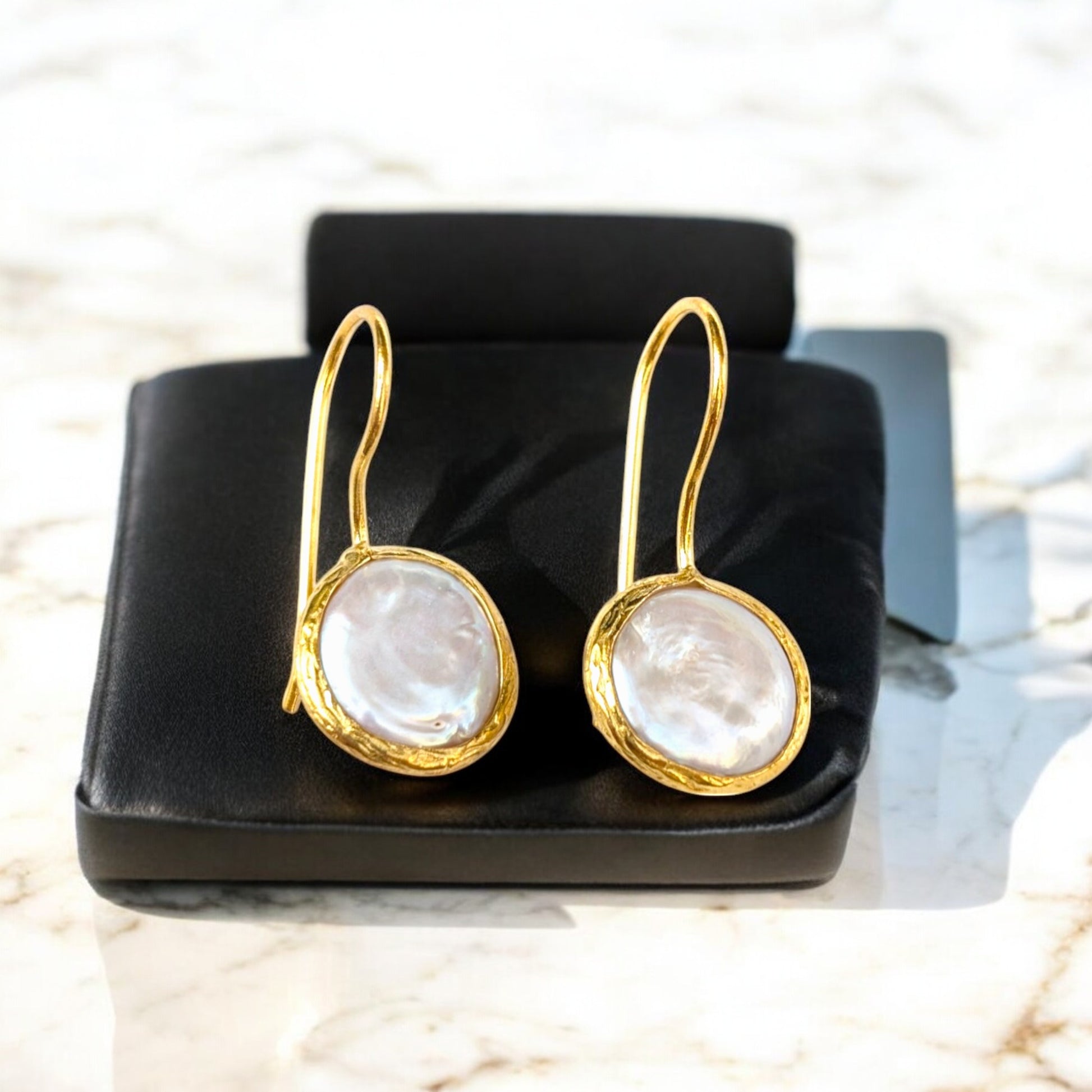 Coin pearl drop earrings with textured gold bezels and iridescent pearls.