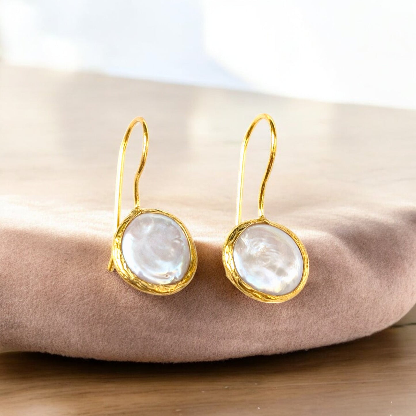Coin pearl drop earrings with textured gold bezels and iridescent pearls.