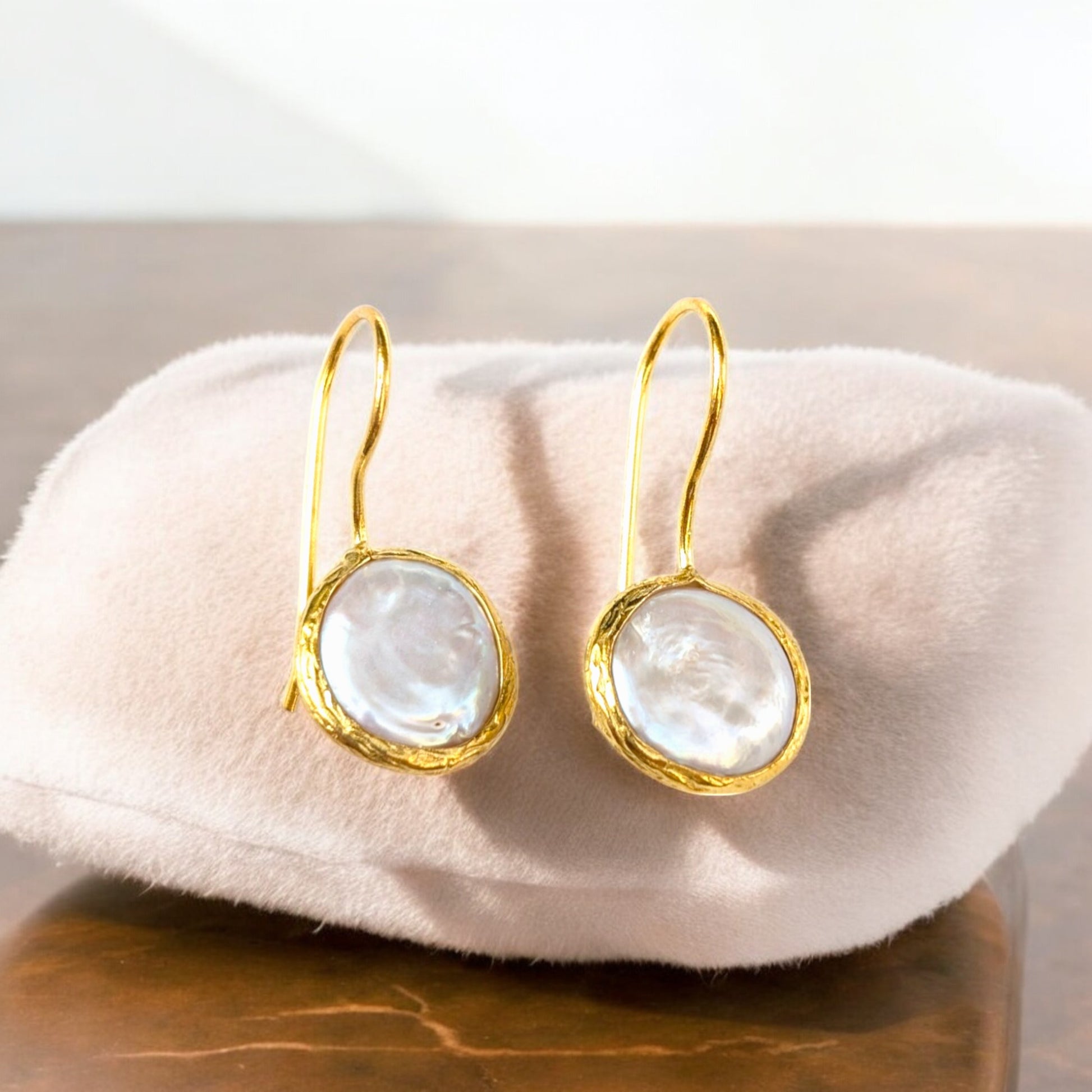 Coin pearl drop earrings with textured gold bezels and iridescent pearls.