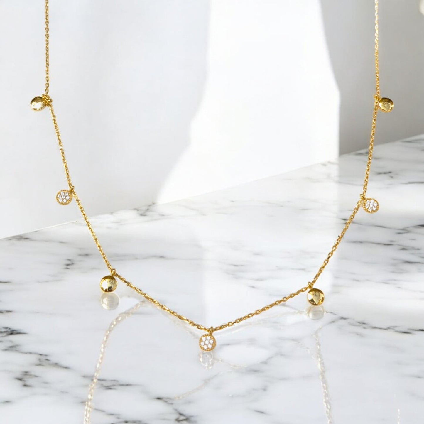 Delicate gold collar necklace with gold discs and clear stone charms