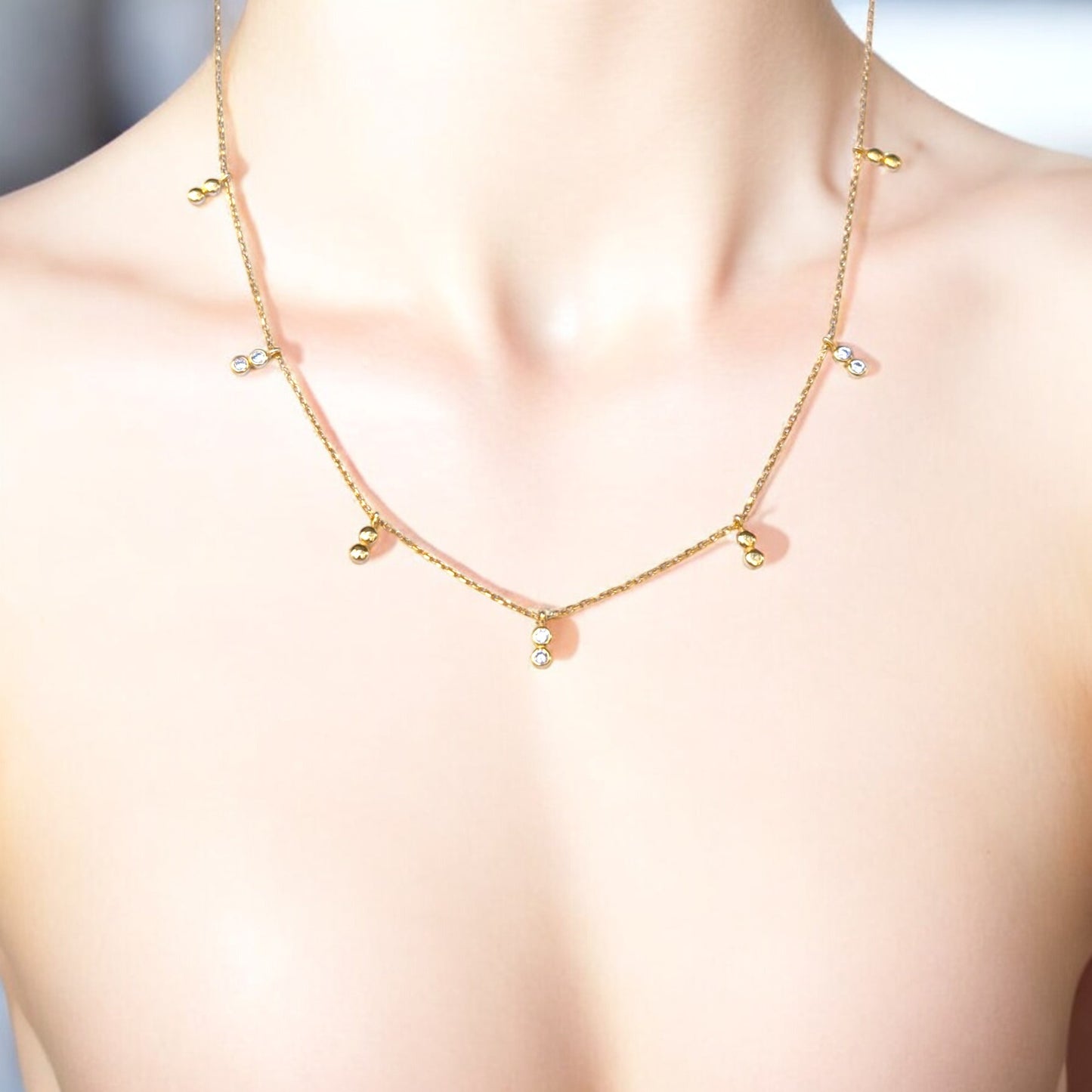 Delicate gold necklace with bezel-set CZ accents.