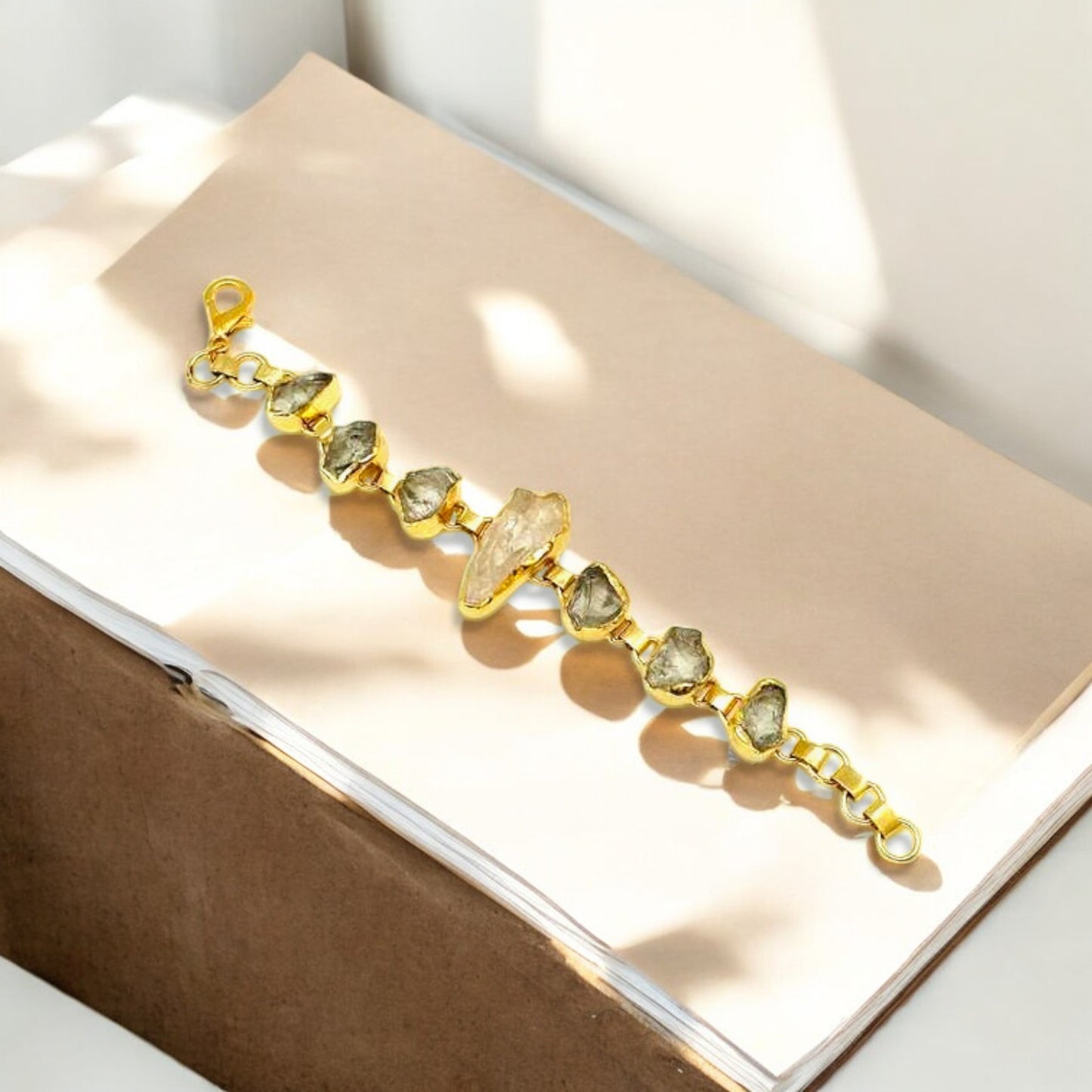 Raw green amethyst and clear quartz bracelet with gold plating on white background