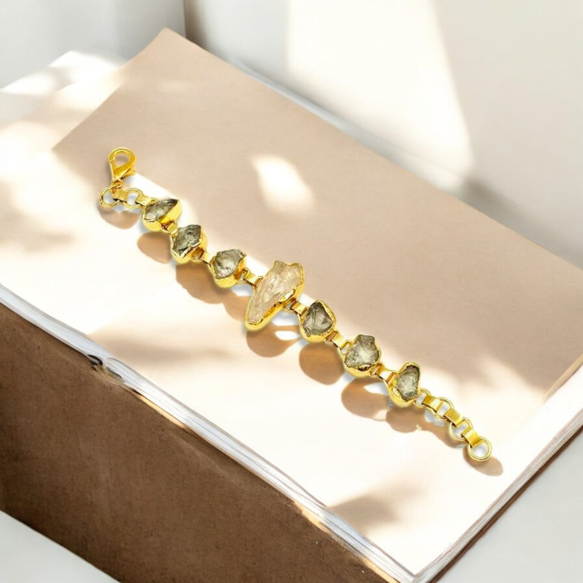 Raw green amethyst and clear quartz bracelet with gold plating on white background