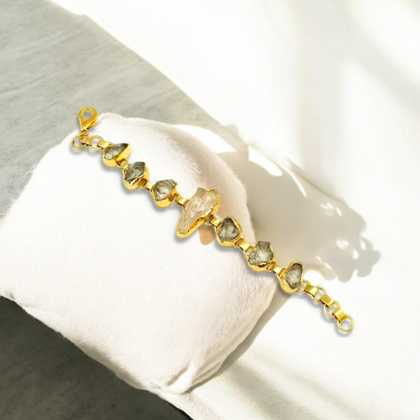 Raw green amethyst and clear quartz bracelet with gold plating on white background