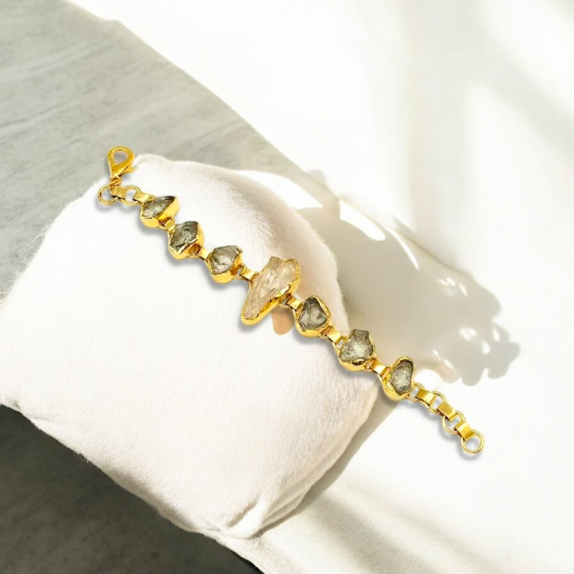 Raw green amethyst and clear quartz bracelet with gold plating on white background