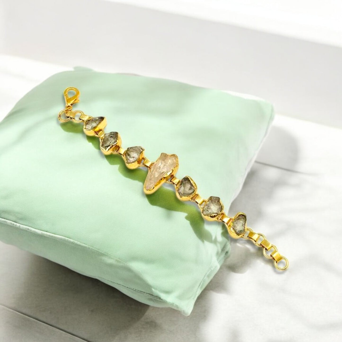 Raw green amethyst and clear quartz bracelet with gold plating on white background